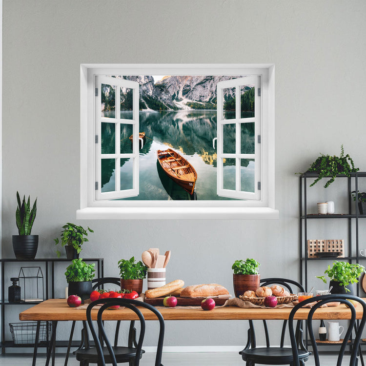 Wandaufkleber-Ansicht-offenes Fenster mit Blick auf ruhigen Bergsee mit Holzruderbooten, umgeben von steilen Felswänden und Wäldern – stimmungsvolle Naturkulisse in den Alpen. Als Dekoidee in einer Küche an einer weissen Wand über einem gedeckten Tisch erklebt.