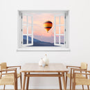 Wandaufkleber mit dem Motiv offenes Fenster mit Blick auf einen Heißluftballon im Sonnenuntergang über einer Berglandschaft – dekoratives 3D-Fensterbild mit Panorama-Effekt. Als Dekoidee über einem Esstisch aus Holz an einer weissen Wand.