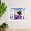 Wandaufkleber: offenes Fenster mit Blick auf ein weitläufiges Lavendelfeld bei Sonnenuntergang, mit einem markanten Baum in der Mitte und sanften Bergen im Hintergrund – romantische Landschaft in Pastellfarben. Als Dekoidee an einer weissen Wand, neben Zimmerpflanzen verklebt.