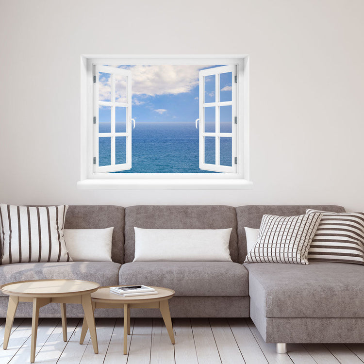 Wandaufkleber-Großansicht: offenes Fenster mit freiem Blick auf das weite, blaue Meer unter leicht bewölktem Himmel – beruhigende Meereskulisse mit Urlaubsfeeling. Als Dekoidee in einem Wohnzimmer, an einer weissen Wand über einer grauen Couch verklebt.