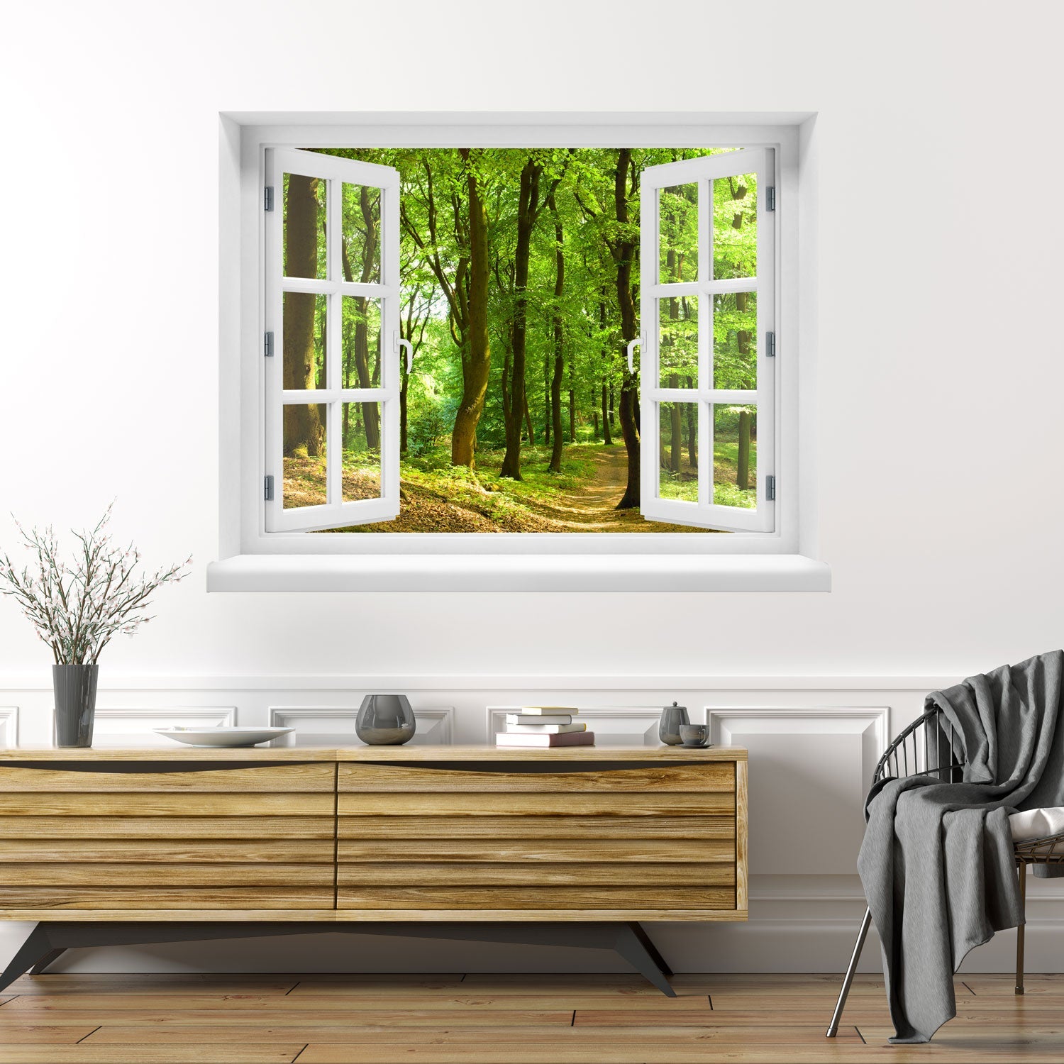 Wandaufkleber Ansicht eines offenes Fenster mit Blick in einen sonnendurchfluteten, grünen Laubwald mit einem schmalen Waldweg – entspannende Naturkulisse mit Frühlings- oder Sommerstimmung. Als Dekoidee in einem Wohnzimmer über einer Holz-Kommode an der weissen Wand verklebt.