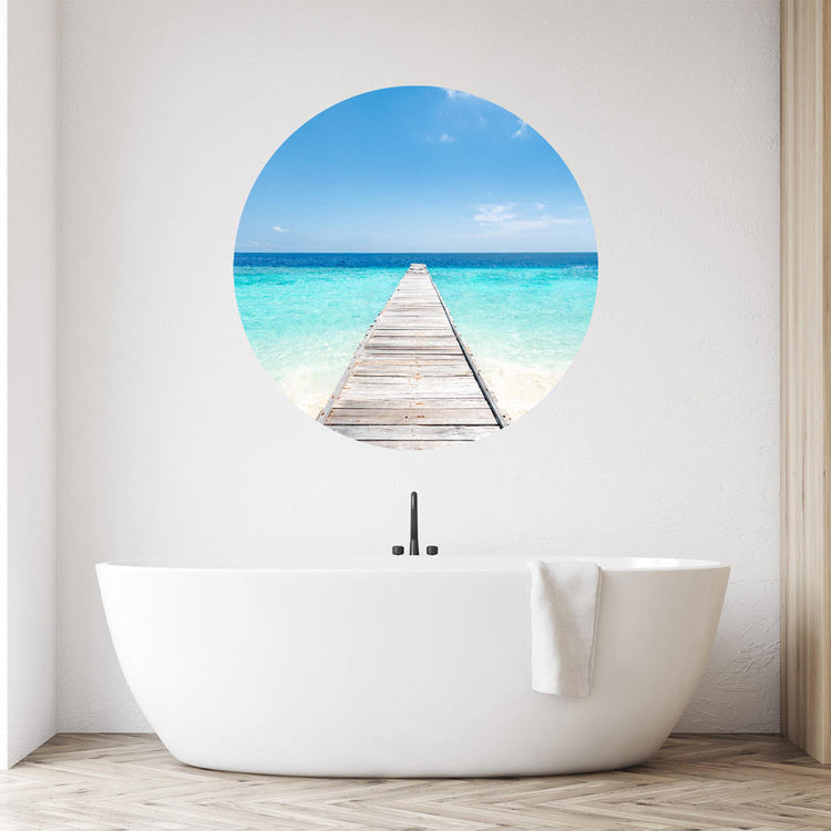 Großansicht eines runden Wandaufklebers mit einem Motiv vom Steg in der Karibik mit blauem Meer. Das Bild schafft einen 3D Effekt und sorgt für eine Tiefe. Als Dekoidee ist es an einer weissen Wand verklebt über einer Badewanne.
