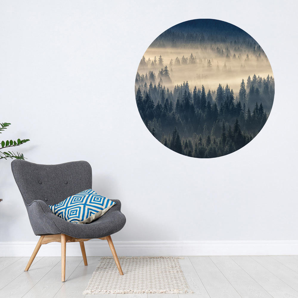 Großansicht eines runden Wandaufklebers mit einem Motiv vom Nebelwald. Das Bild schafft einen 3D Effekt und sorgt für eine Tiefe. Als Dekoidee ist es an einer weissen Wand verklebt über einem grauen Sessel.