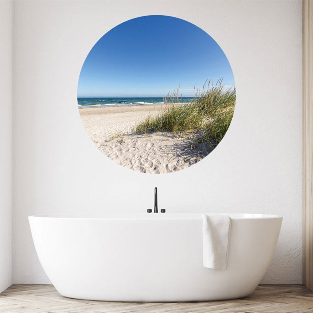 Großansicht eines runden Wandaufklebers mit einem Motiv von Ostseedünen, Strand und dem Meer. Das Bild schafft einen 3D Effekt und sorgt für eine Tiefe. Als Dekoidee ist das Wandtattoo an einer weissen Wand verklebt über einer Badewanne.