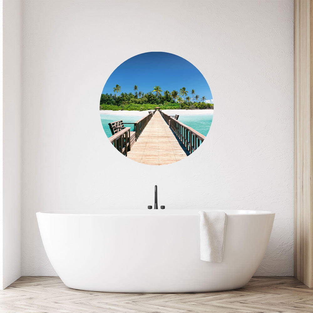 Großansicht eines runden Wandaufklebers mit einem Motiv von Palmen in einer Lagune. Das Bild schafft einen 3D Effekt und sorgt für eine Tiefe. Als Dekoidee ist das Wandtattoo an einer weissen Wand verklebt über einer Badewanne.