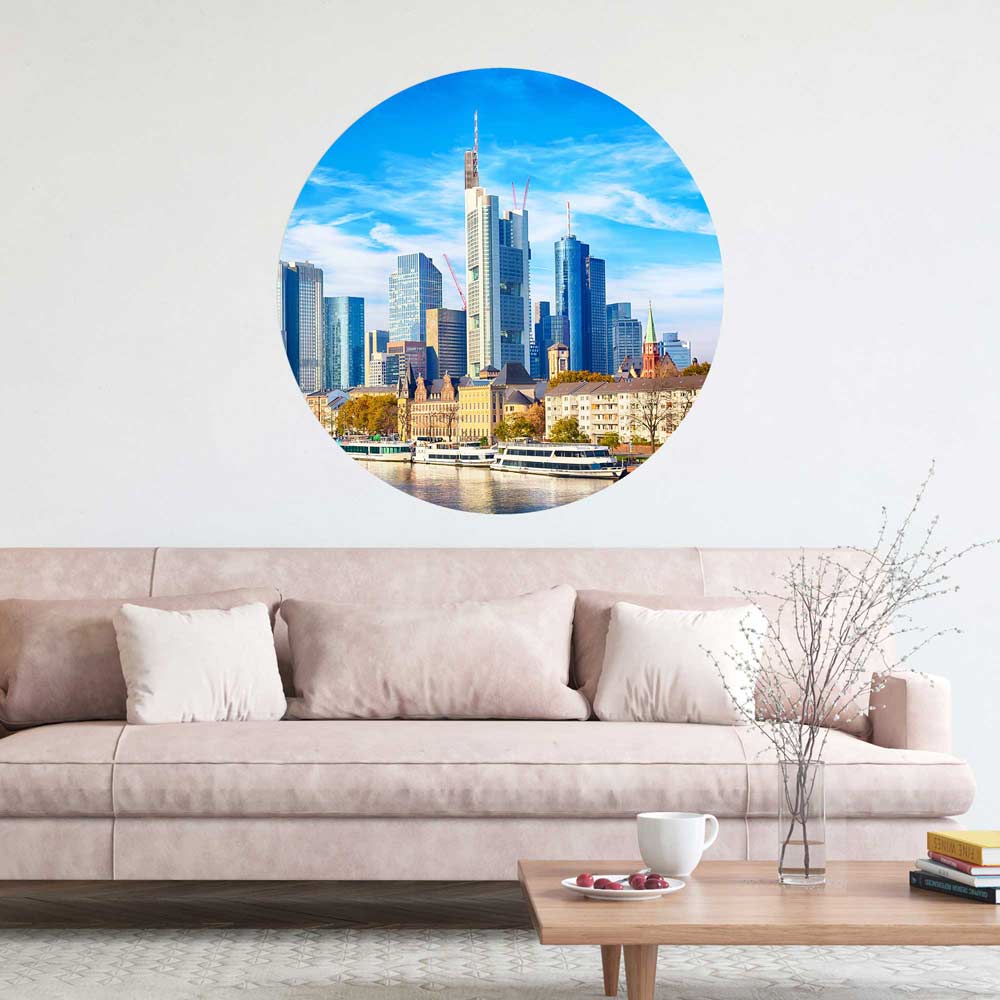 Rundes Wandbild mit der Skyline von Frankfurt am Main, stilvoll über einem modernen Sofa im Wohnzimmer dekoriert.