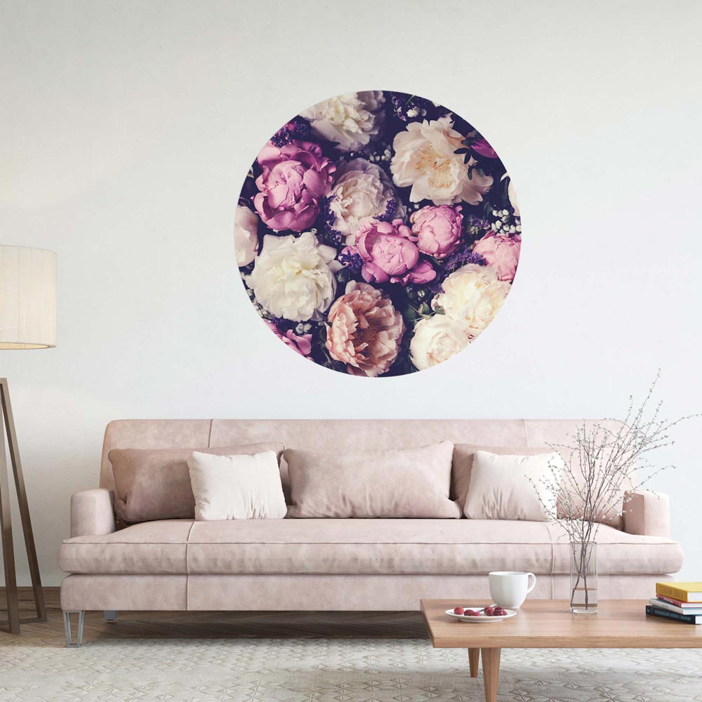 Großer runder Wandsticker mit romantischen Pfingstrosen in Rosa, Creme und Violett, stilvoll platziert über einem beigen Sofa im Wohnzimmer.