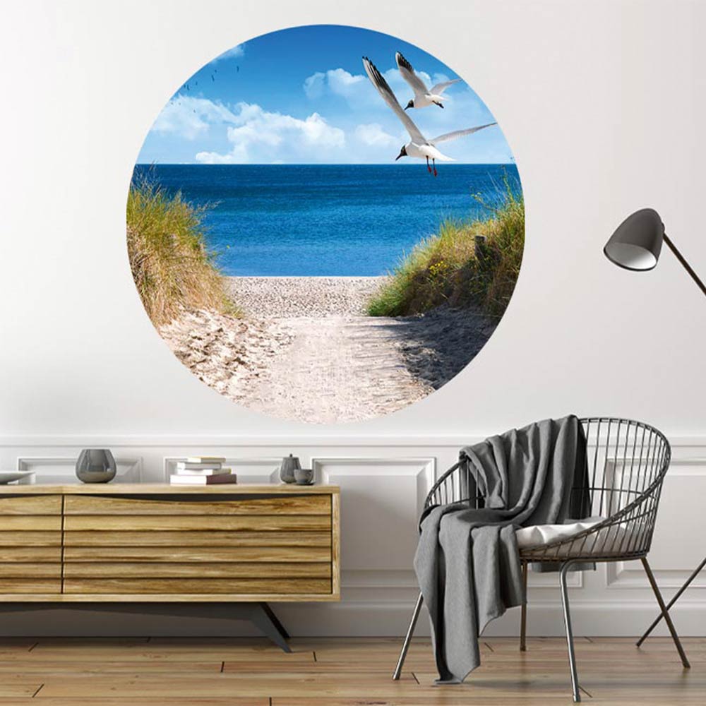 Großansicht eines runden Wandaufklebers mit einem Motiv am Strand mit Möwen. Das Bild schafft einen 3D Effekt und sorgt für eine Tiefe. Als Dekoidee ist das Wandtattoo an einer weissen Wand verklebt über einer Kommode in einem Wohnzimmer.