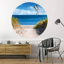 Großansicht eines runden Wandaufklebers mit einem Motiv am Strand mit Möwen. Das Bild schafft einen 3D Effekt und sorgt für eine Tiefe. Als Dekoidee ist das Wandtattoo an einer weissen Wand verklebt über einer Kommode in einem Wohnzimmer.