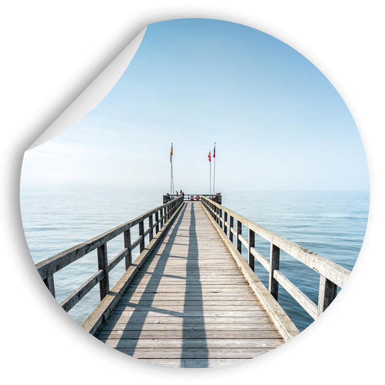 Großansicht eines runden Wandaufklebers mit einem Motiv vom Steg in der Nordsee. Das Bild schafft einen 3D Effekt und sorgt für eine Tiefe. Eine Ecke des Wandtattos ist abgezogen.