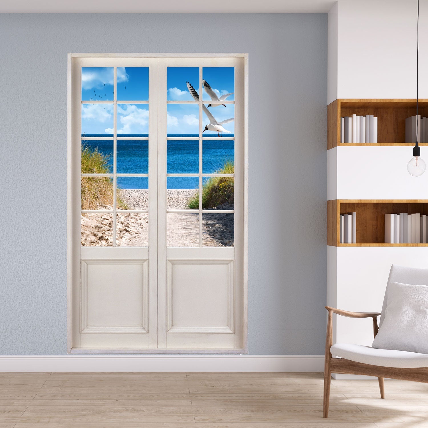Leseecke mit Terassentür-Aufkleber, zum Strand und Meer mit dem Motiv: "Ostsee und Möwen" neben einem Bücherregal.