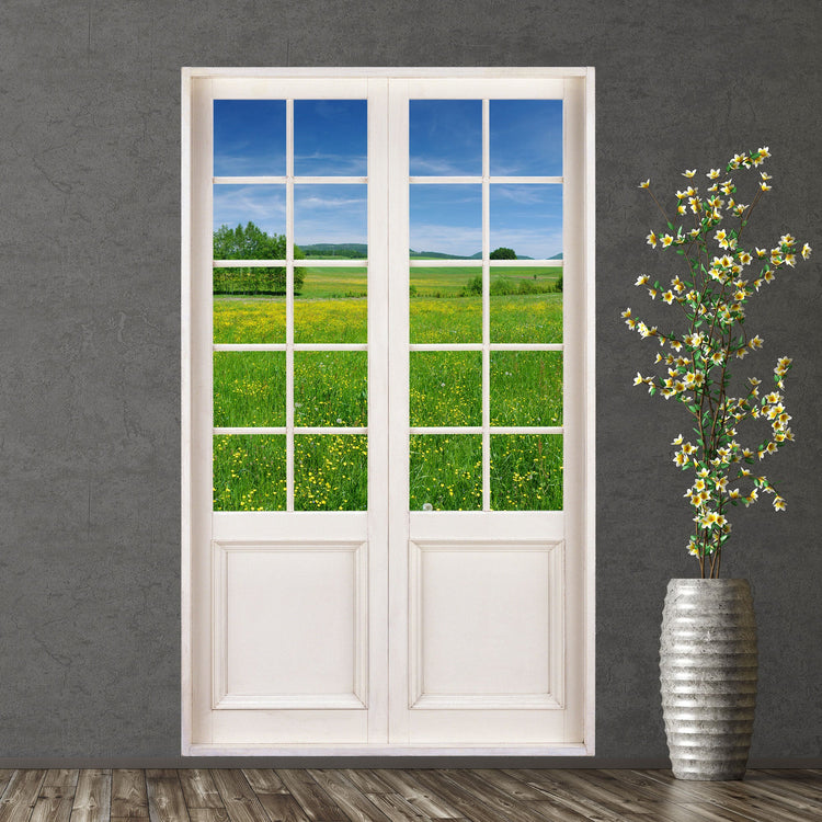 Wandaufkleber mit den Foto einer Terrassentür und Aussicht auf sommerliche Blumenwiese. Hier als Beispiel an einer grauen Wand neben einer Bodenvase.