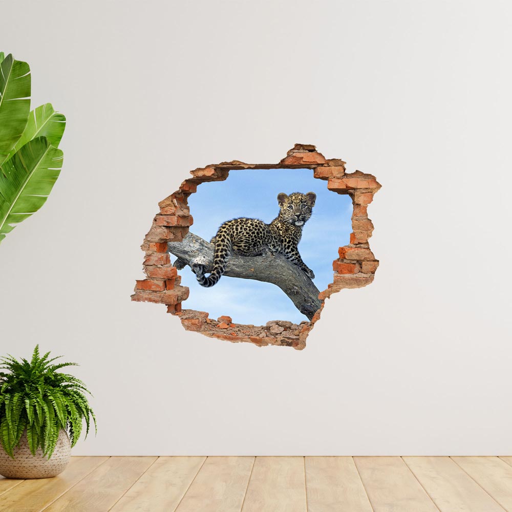 Wandtattoo - Mauerdurchbruch "Leopardenbaby" auf weißer Wand neben großen Zimmerpflanzen verklebt.
