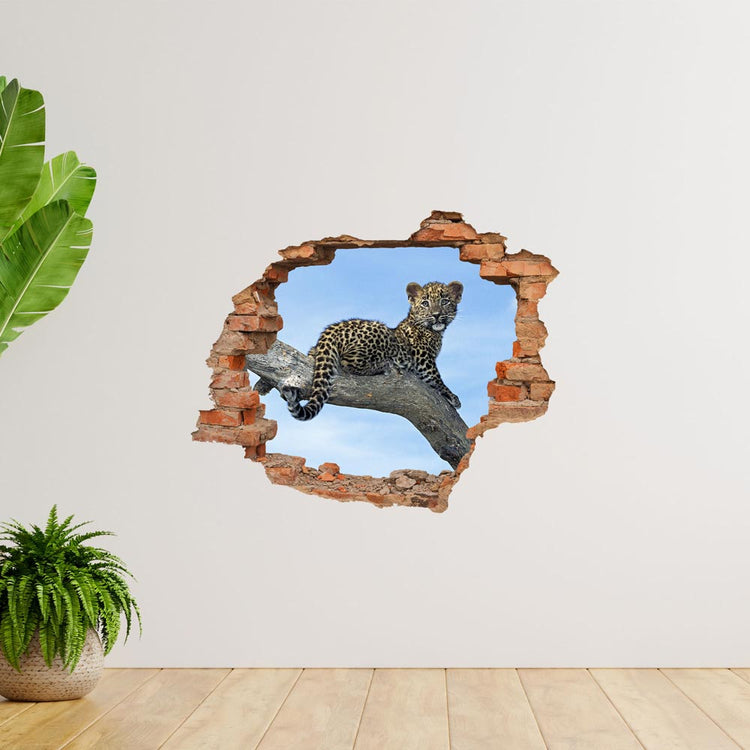 Wandtattoo - Mauerdurchbruch "Leopardenbaby" auf weißer Wand neben großen Zimmerpflanzen verklebt.