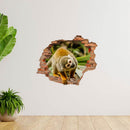 Wandtattoo - Wanddurchbruch "Affe" auf weißer Wand verklebt, neben großen Zimmerpflanzen.