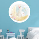 Wandtattoo rund "Mond und Hasen" auf blauer Wand im Kinderzimmer neben einem Bett.