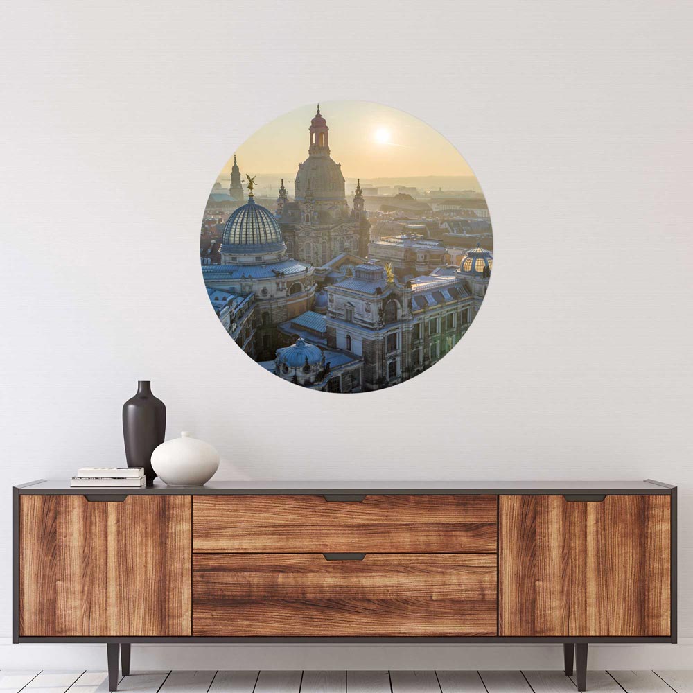 Rundes Wandtattoo der Dresdner Frauenkirche bei Sonnenaufgang, stilvoll präsentiert über einer modernen Holzkommode.