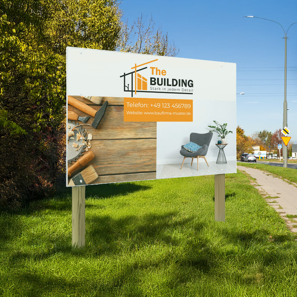 Das Bild zeigt ein großes Werbeschild am Straßenrand mit dem Logo und der Kontaktdaten eines Bauunternehmens namens 'The BUILDING'. Auf dem Schild sind Werkzeuge sowie ein Wohnzimmer mit einem Stuhl und einer Pflanze abgebildet. Das Schild steht auf zwei Holzmasten.